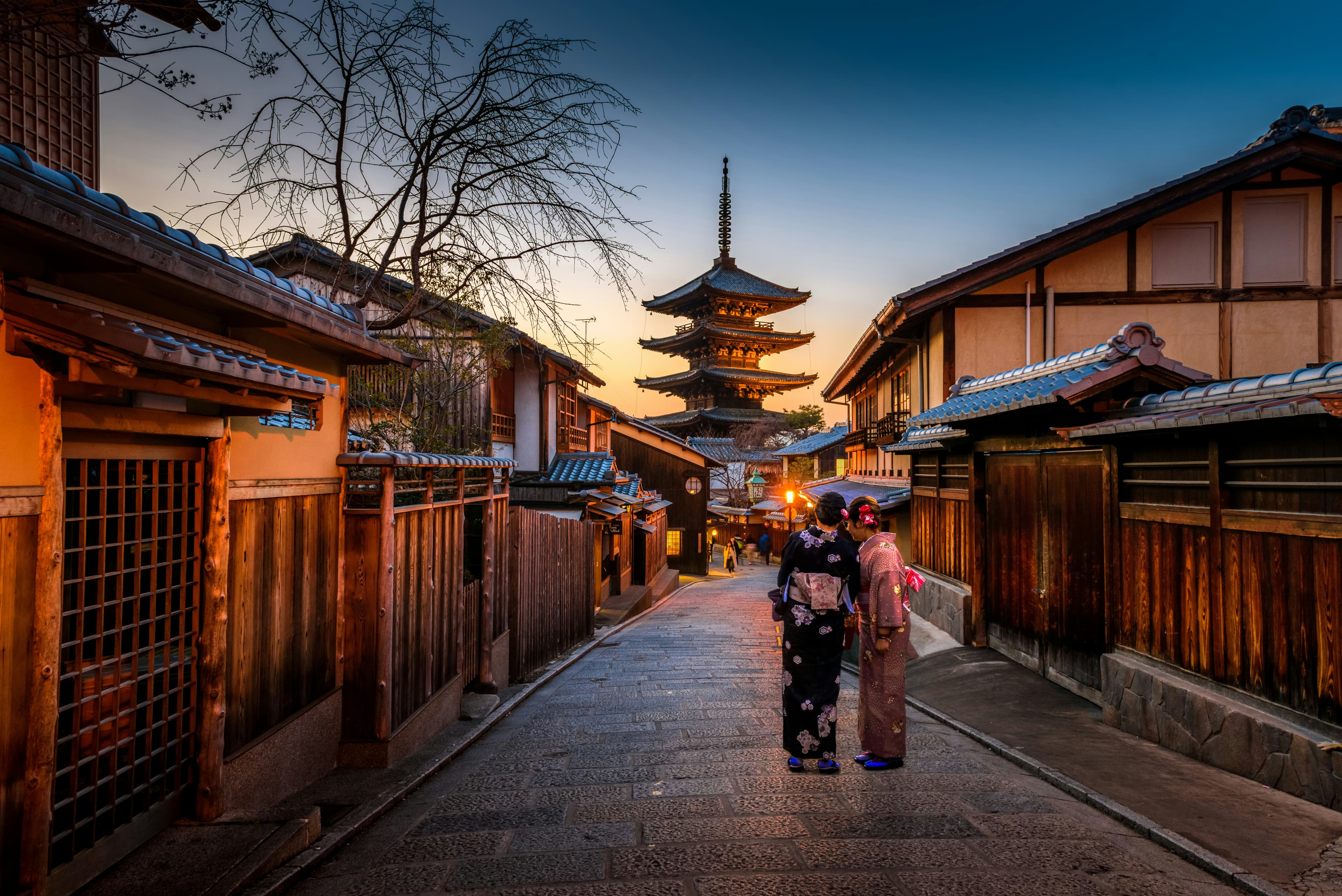 Two women in kimono walking toward a pagoda at golden hour in Tokyo